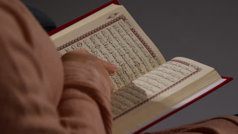 Close-Up-Of-Muslim-Woman-Sitting-On-Sofa-At-Home-Reading-Or-Studying-The-Quran-3